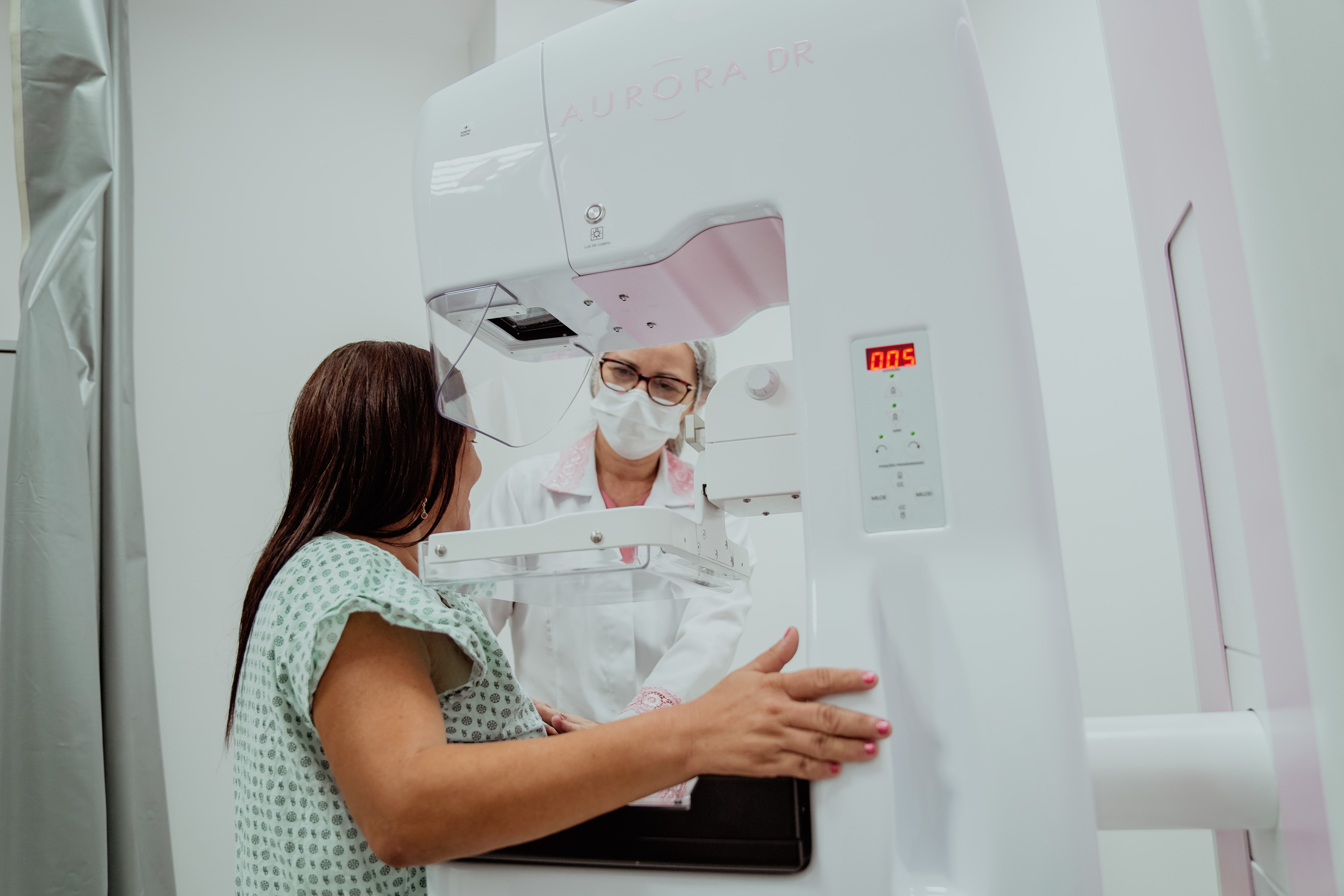 enfermeira atendendo uma mulher na máquina de mamografia